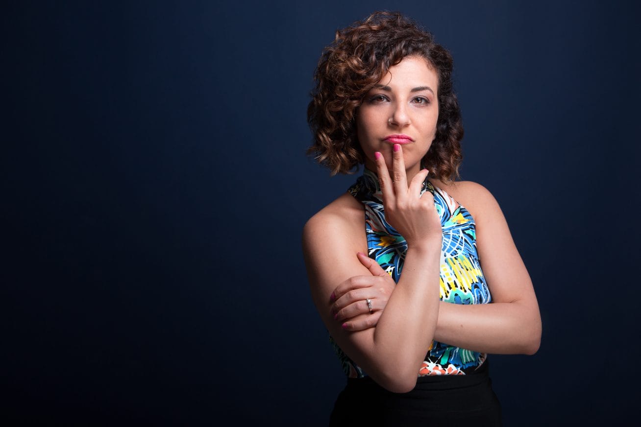 A woman in a blue and yellow short sleeved vest top poses at the camera