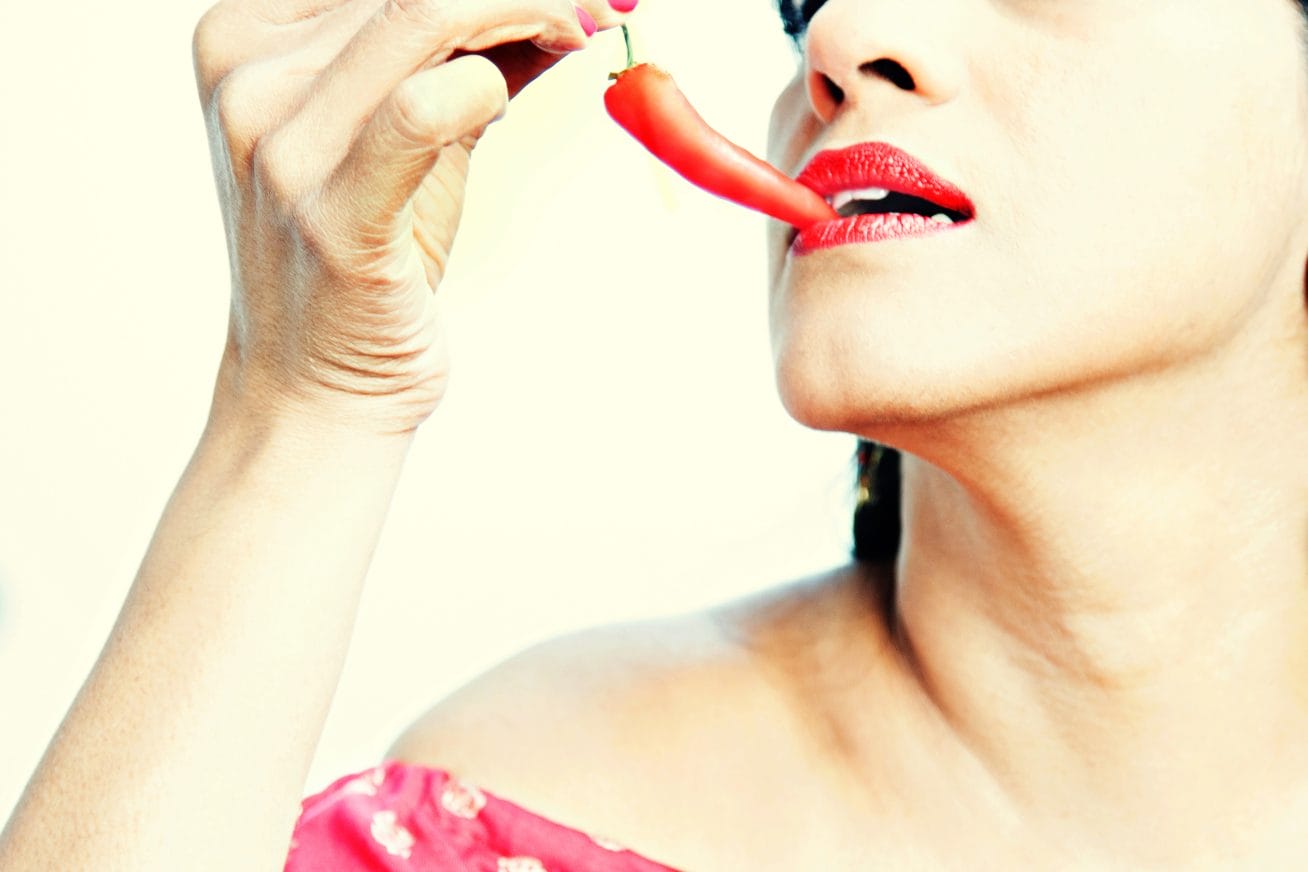 A woman bites the tip of a chilli pepper