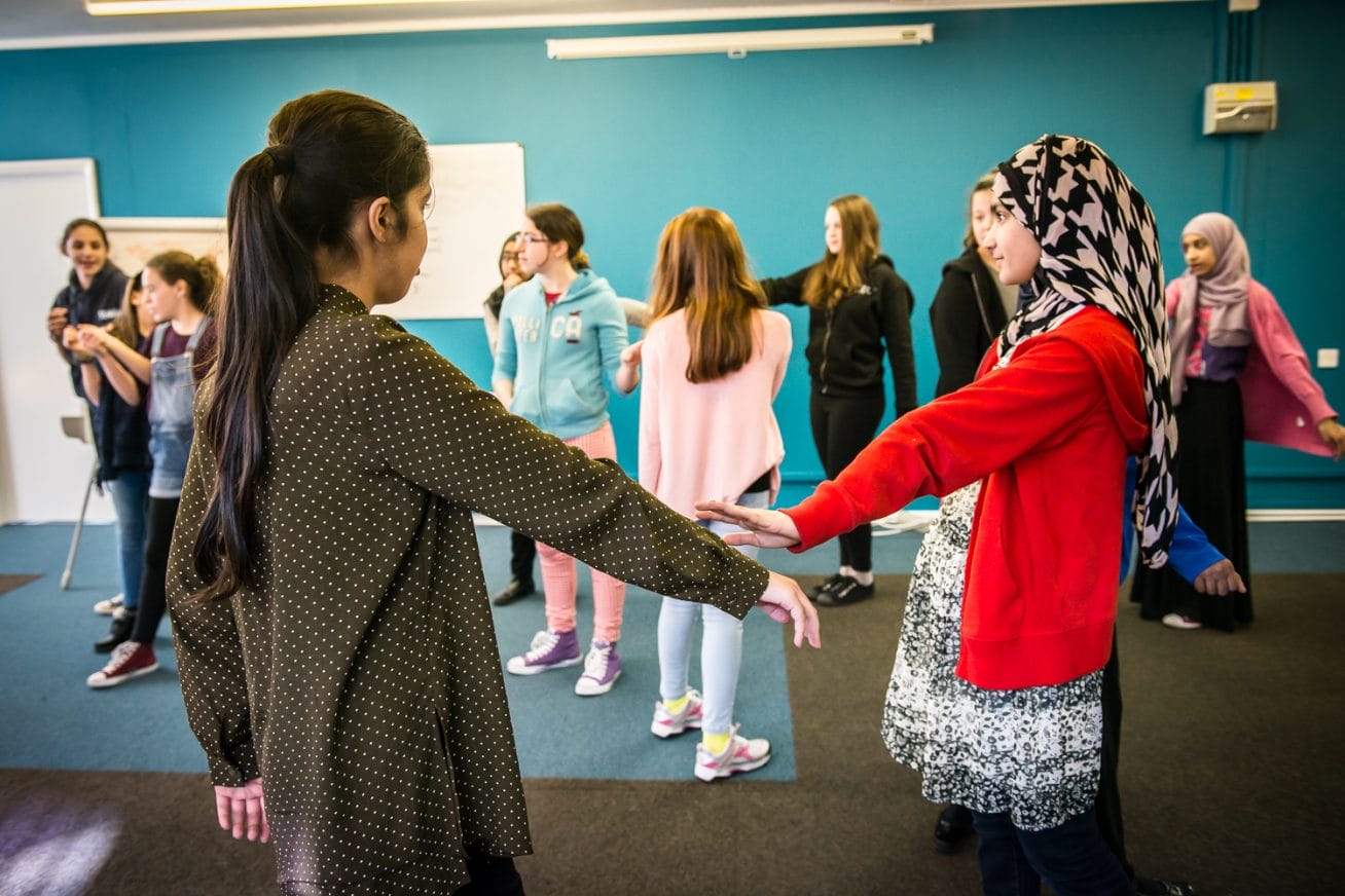 A group of children stand in a circle holding hands
