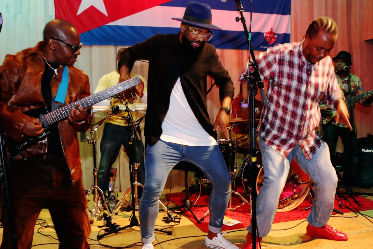 A band are pictured dancing mid-performance