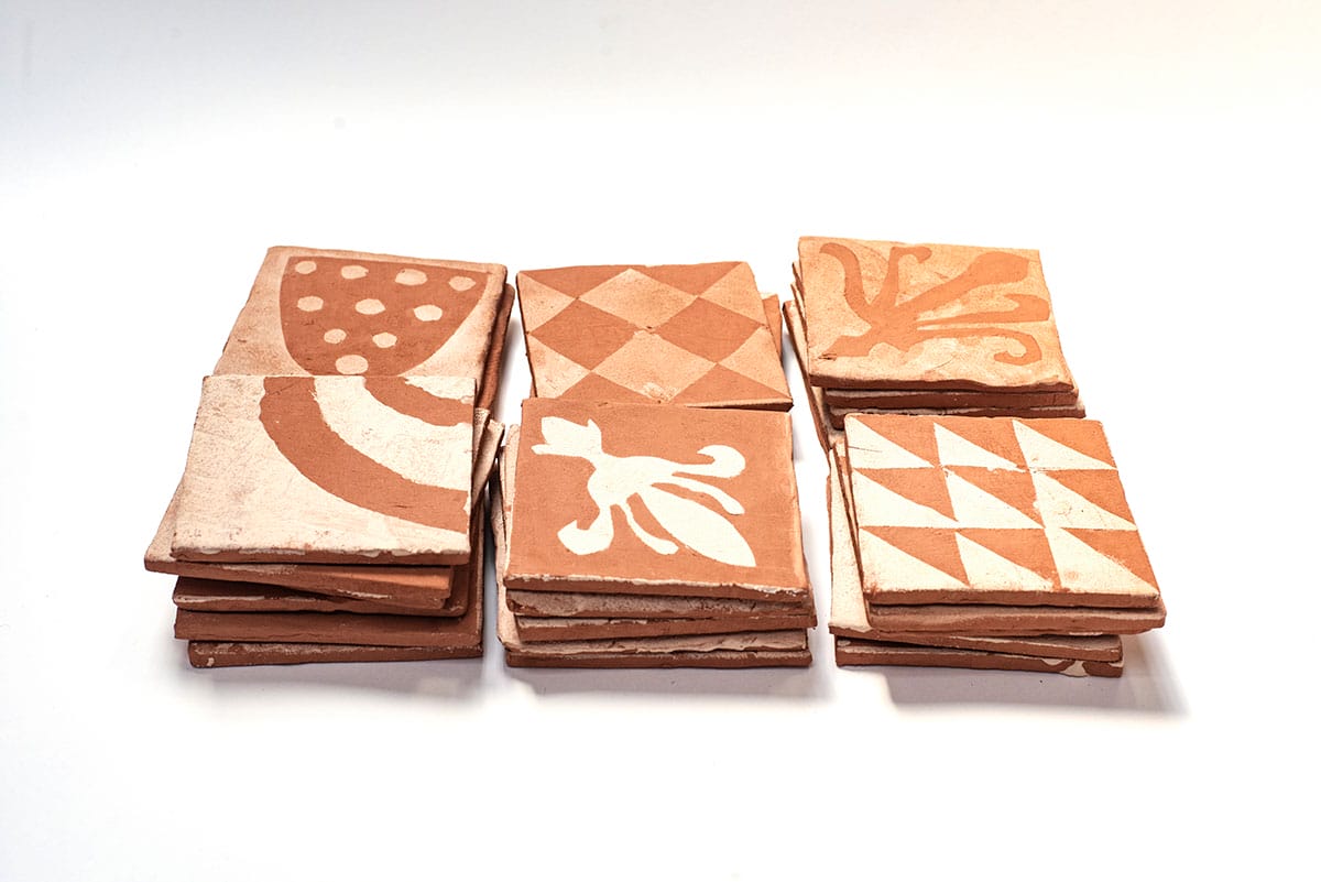 Terracotta tiles with white patterns, made by children at local primary schools