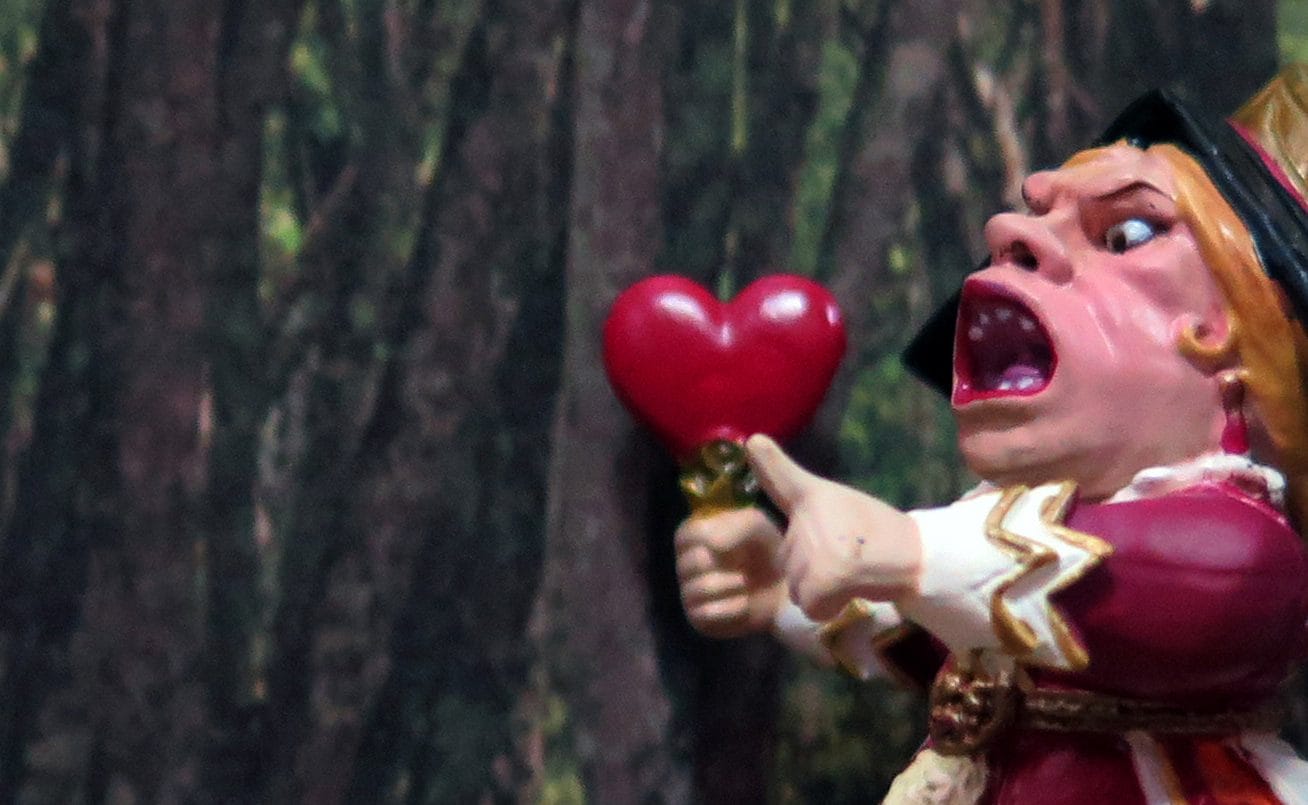 A drawing of the queens of hearts holding up a heart and pulling a face at it