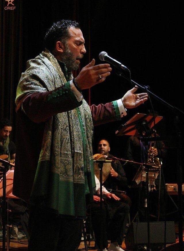 A man sings into a microphone on stage