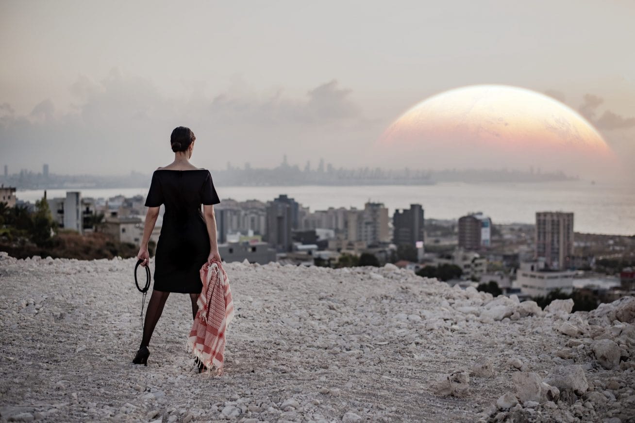 a woman stands looking at the sun setting