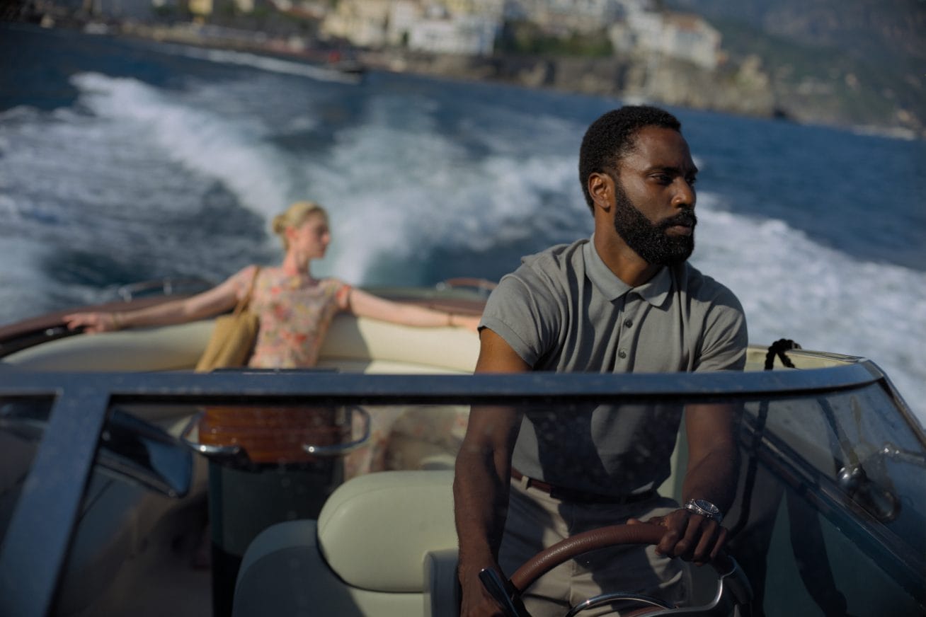 John David Washington driving a speedboat with Elizabeth Debick sitting in the back