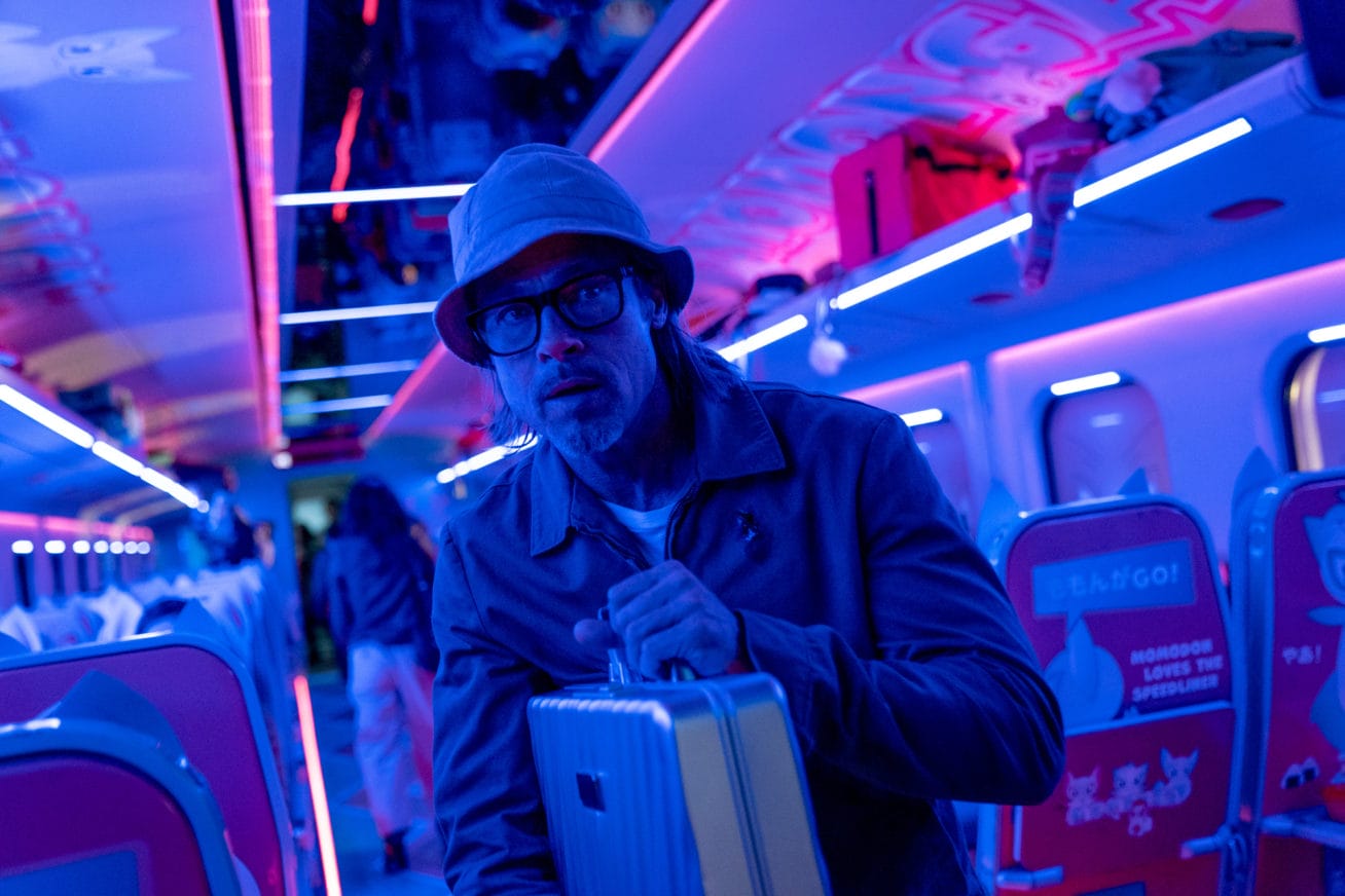Man carrying suitcase in a dimly lit train carriage